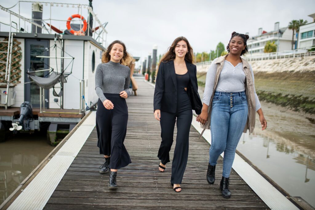 Three young women happily walking on a pier in Portugal, enjoying a moment of friendship and joy.